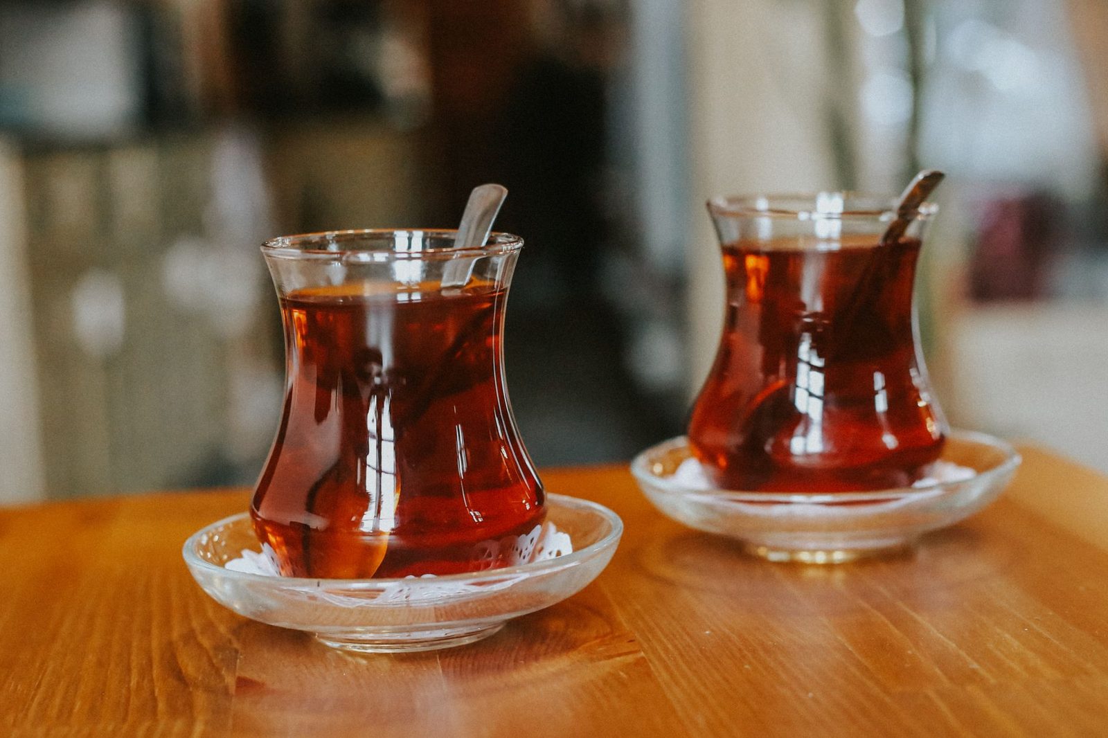 Ahşap bir masada yan yana duran, ince belli iki bardak çay