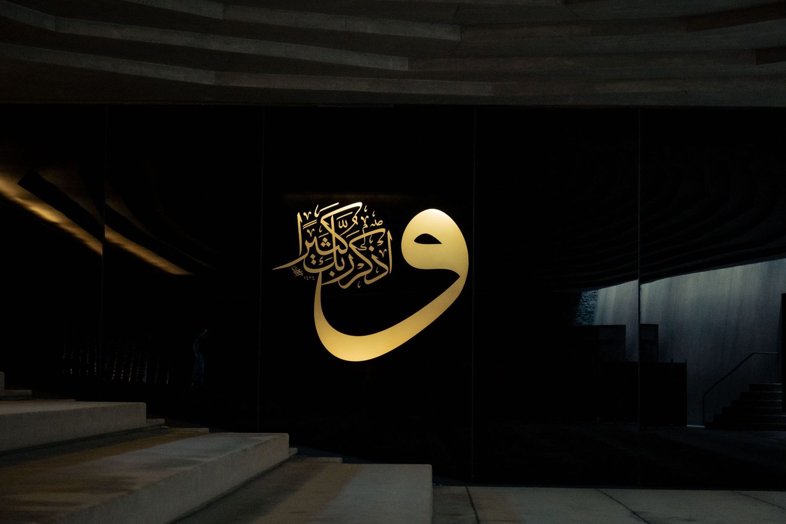 Sabah ışığında duvara asılı el yazması bir hat levhası ve altındaki ahşap raf