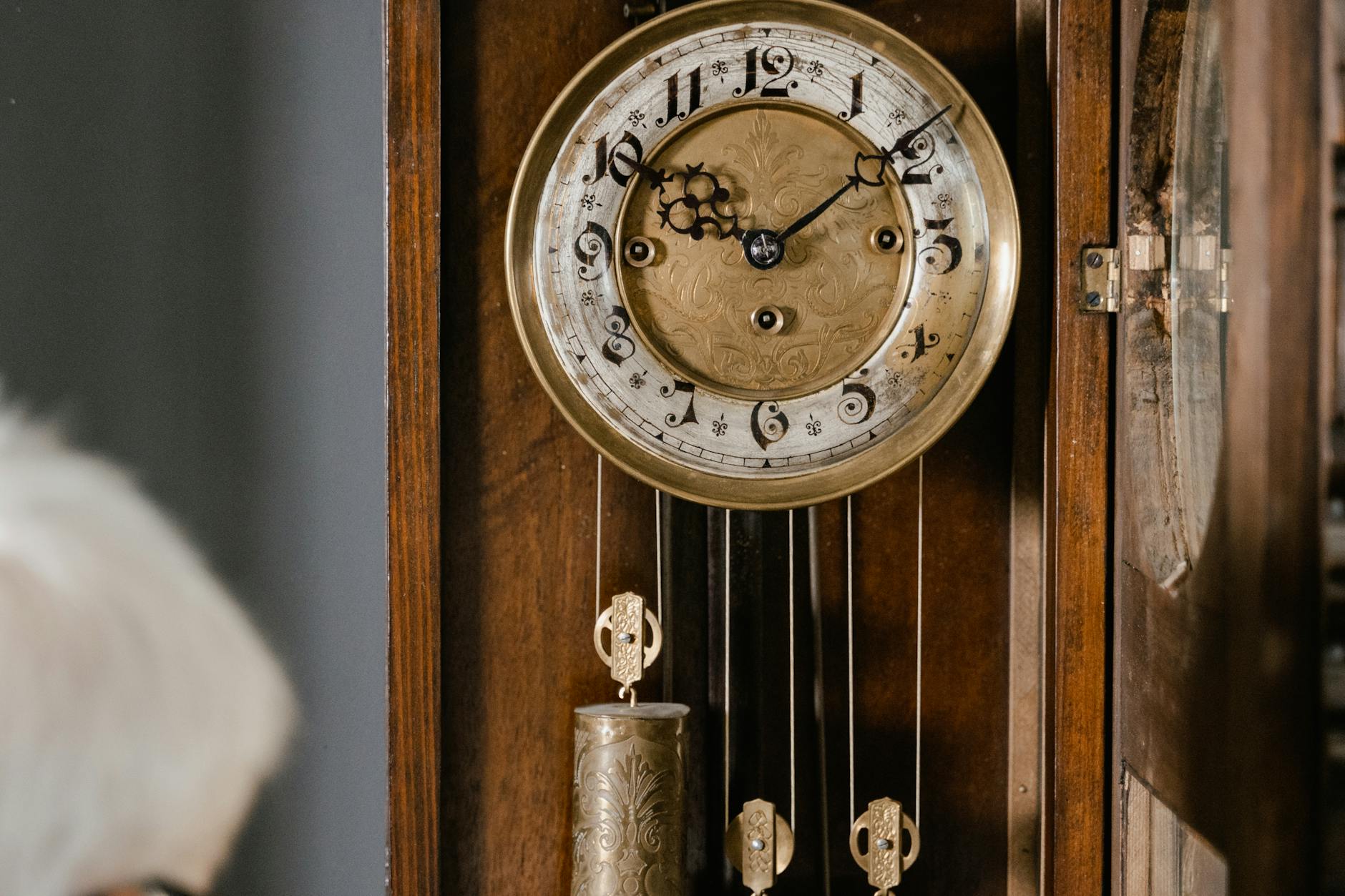 Brass pendulum clock mechanism mid-swing in amber light, Hermetic Principle of Rhythm