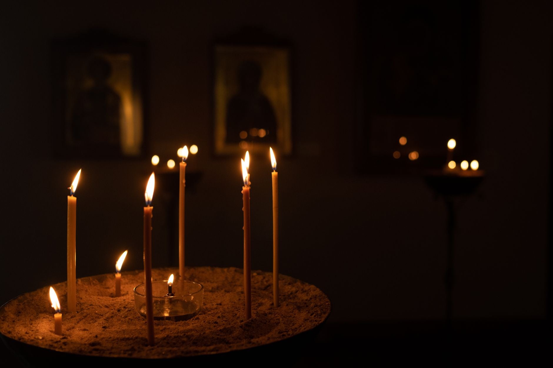 Candle flame in a dark altar space, the moment of closing a ritual working