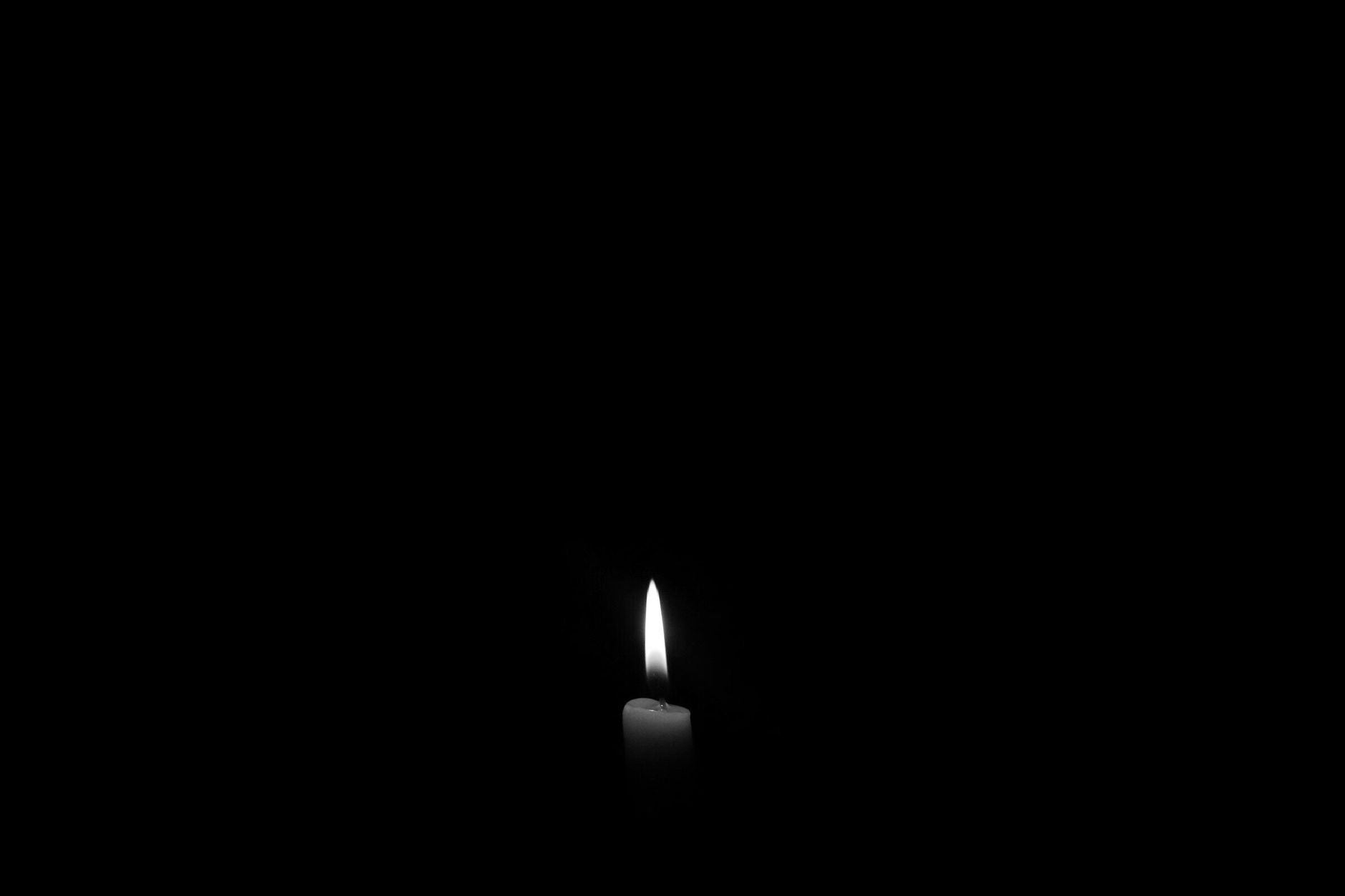 Single candle flame in darkness — bare awareness without object in deep meditation
