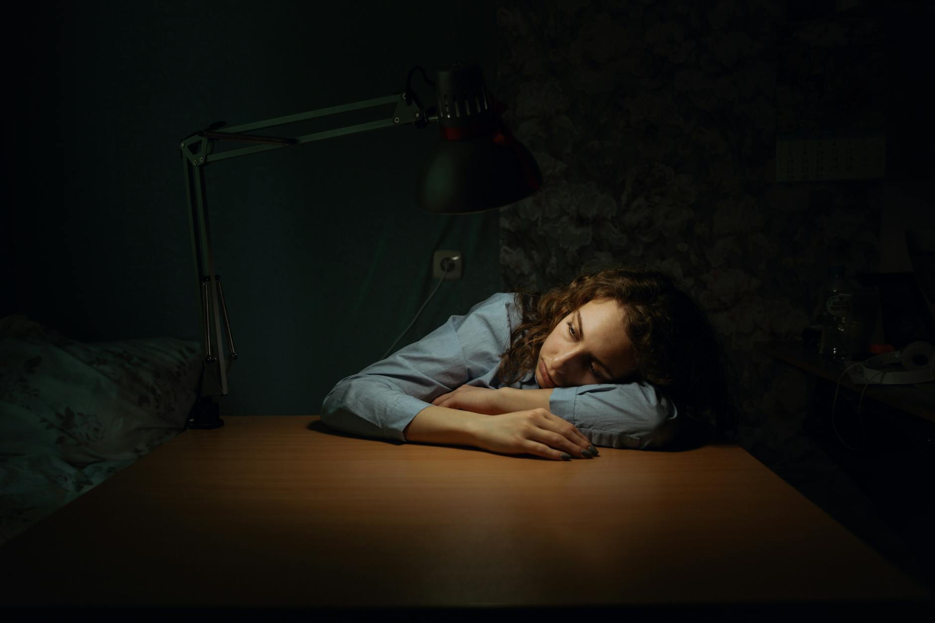 A woman slumped at a desk in daytime, the heavy fatigue people misread as ordinary stress