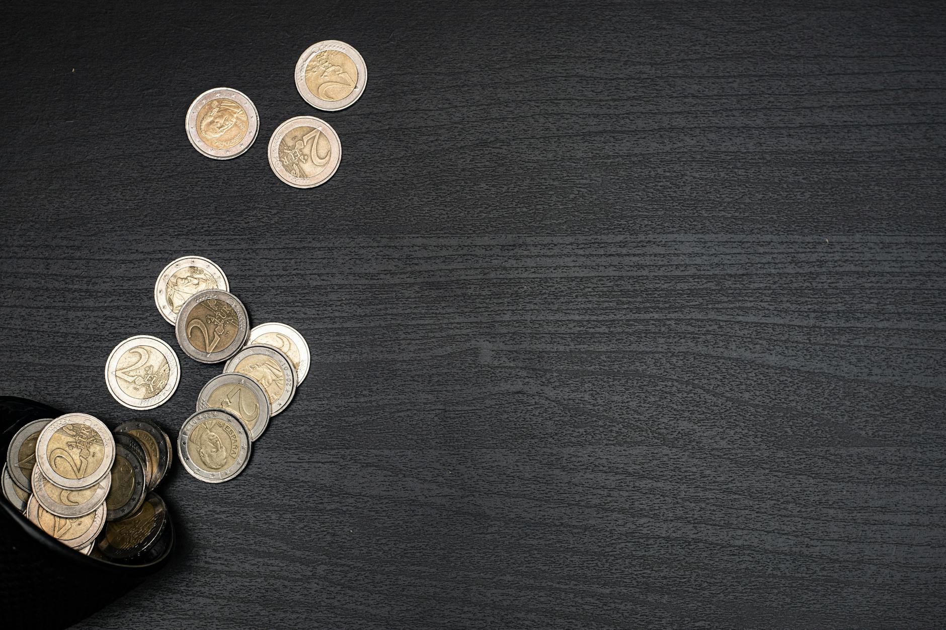 Gold coins scattered across dark fabric, evoking the suddenness of unexplained financial loss