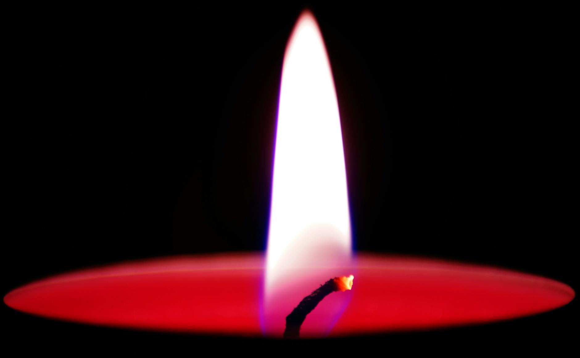 A single lit candle flame burning steadily in darkness