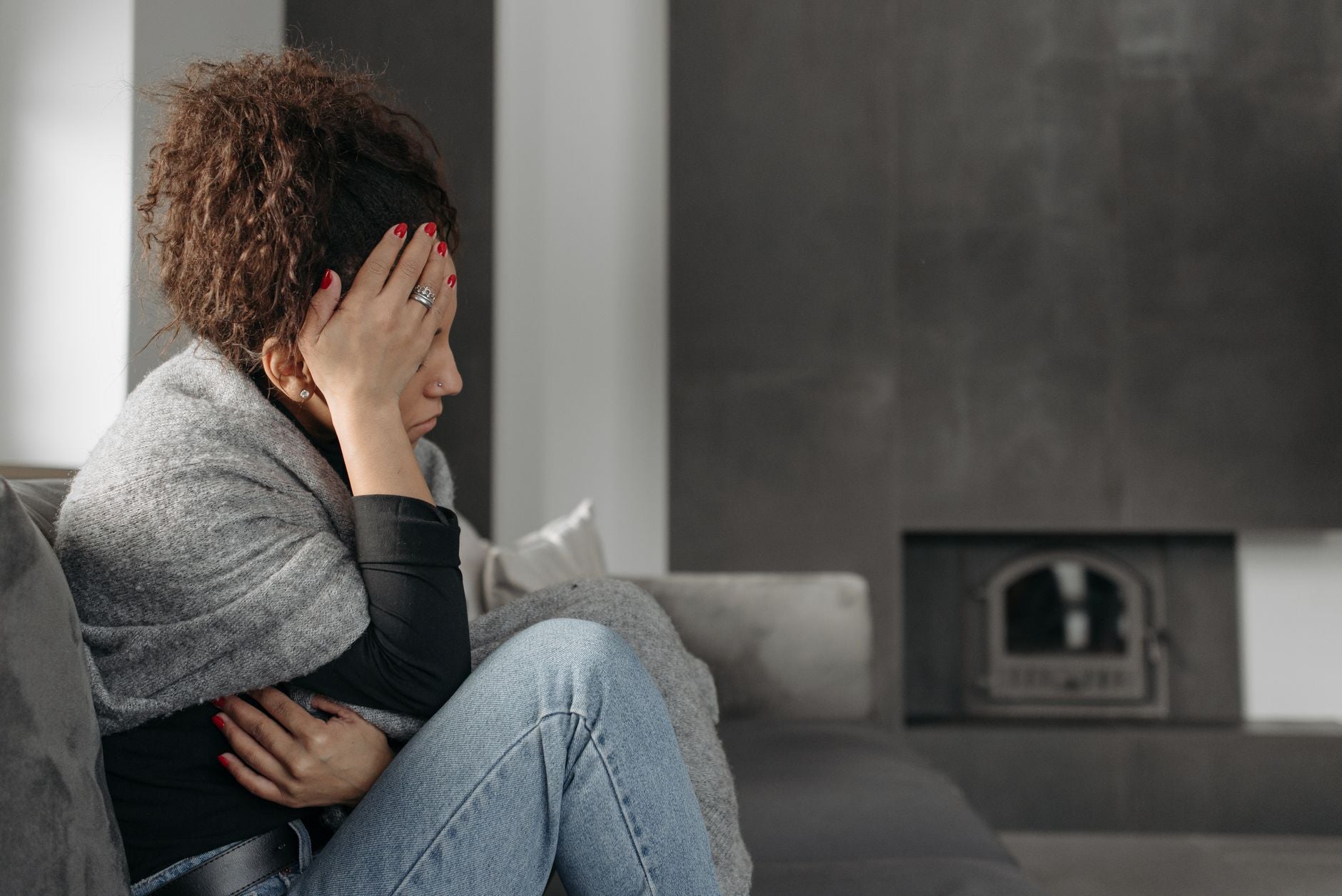 Woman sitting with visible discomfort representing inner-state and energy-field disruption
