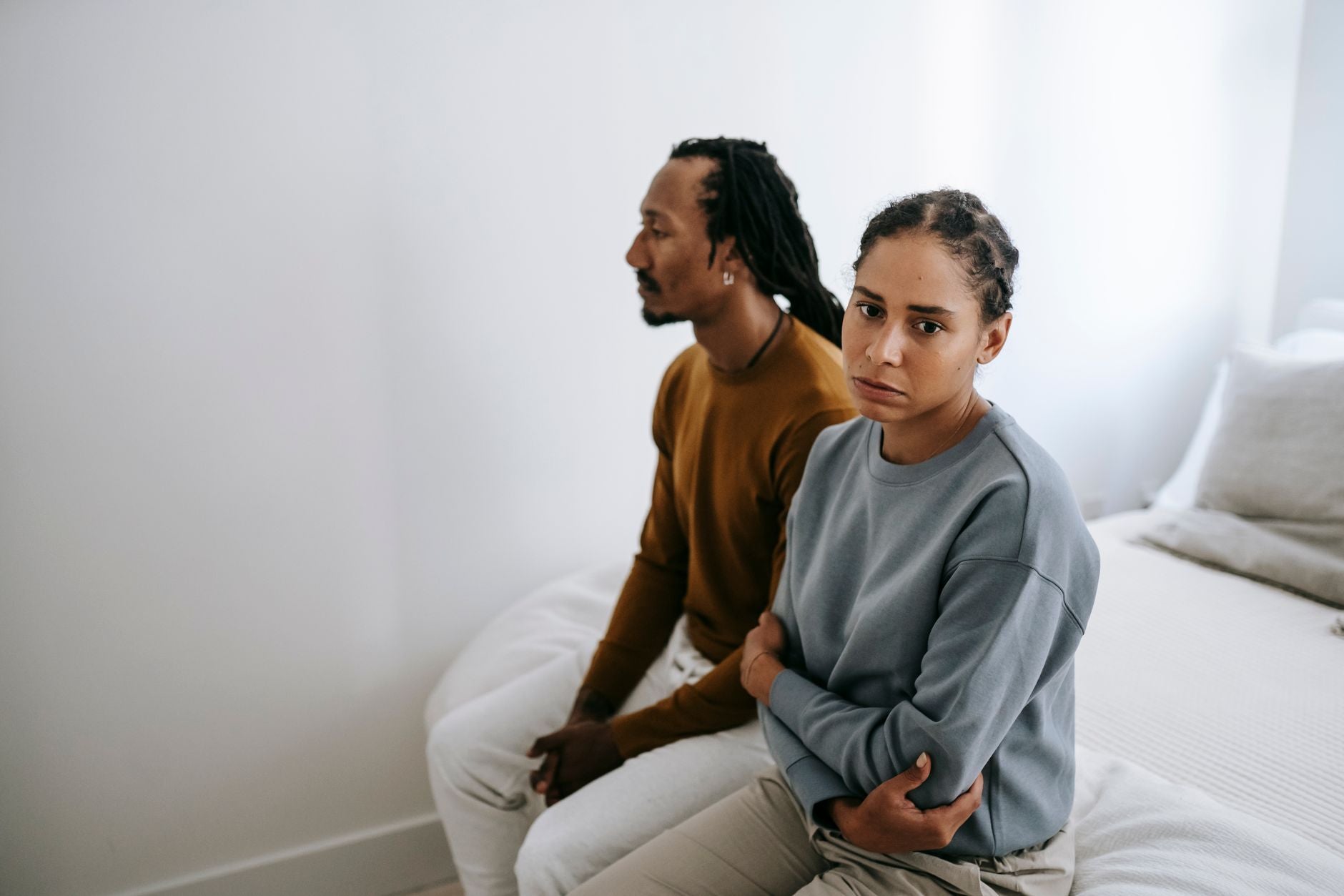 Couple sitting apart on a bed in silence, illustrating an inherited relational pattern repeating in the present