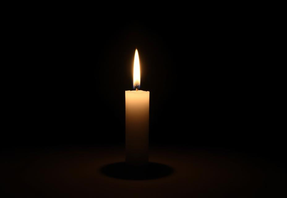 A single white candle burning in a dark room — the quiet signal of a formal close marking the deliberate end of the day's spiritual practice