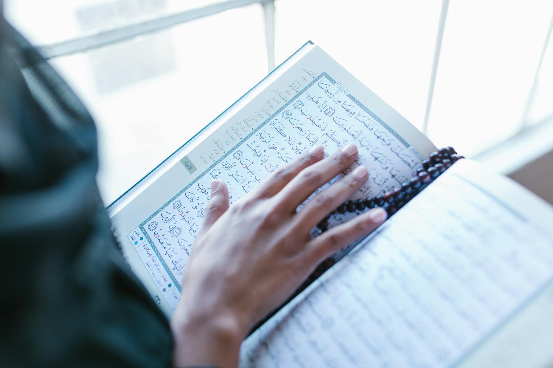 Person holding open religious text during recitation practice