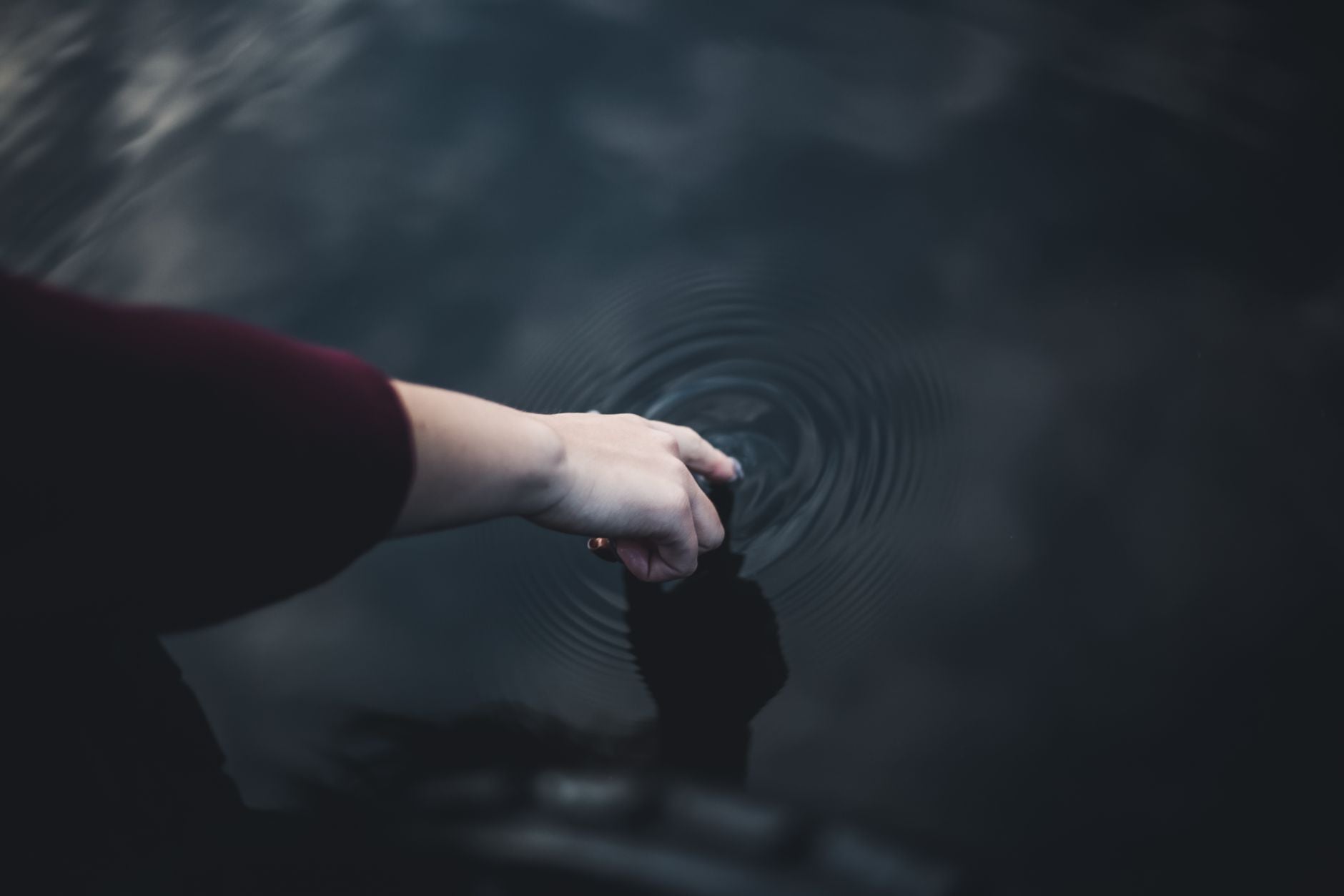 Stone dropping into still water creating expanding ripples, representing causal chain reaction