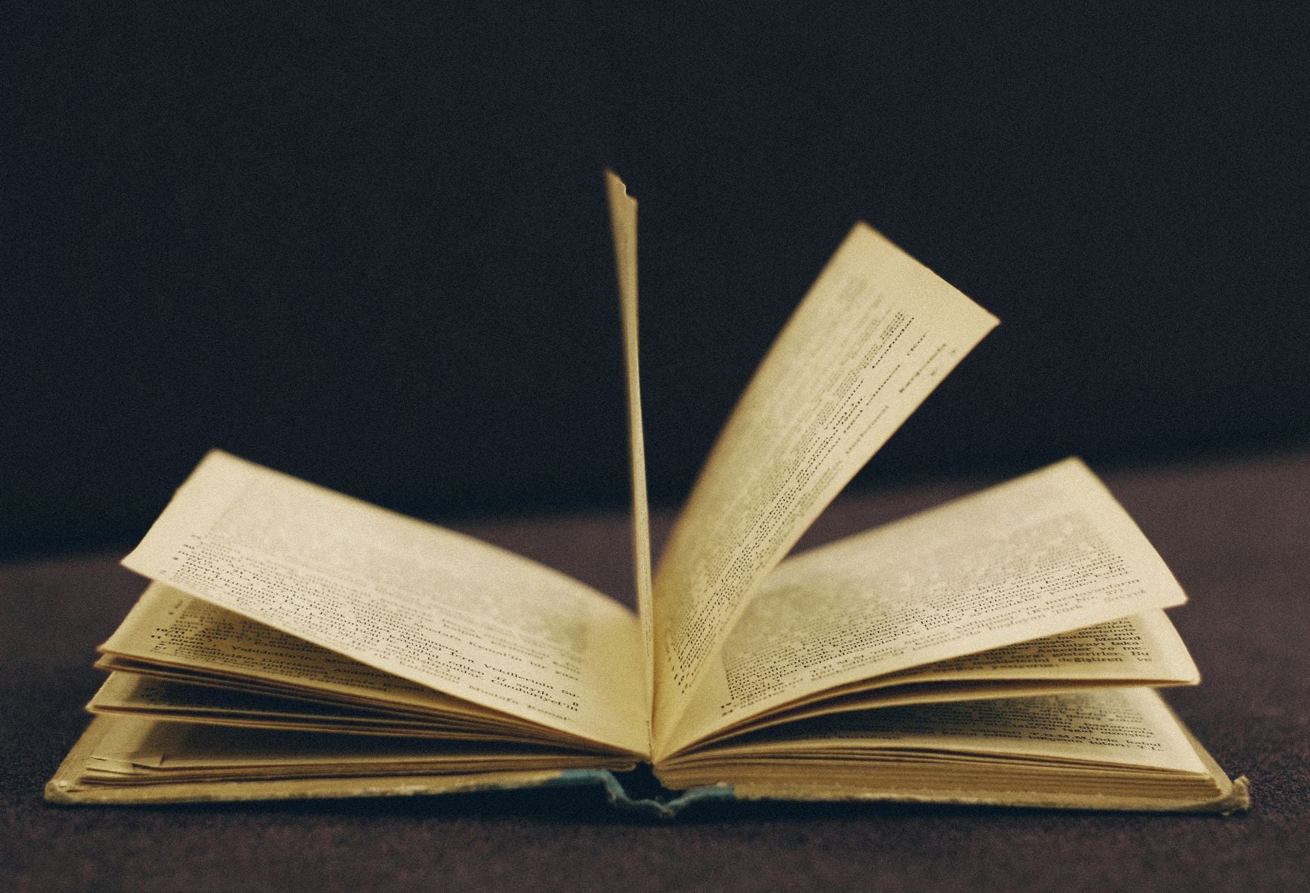 An old leather-bound book opened on a wooden surface beside a brass key, illustrating the Kybalion's Master-Key chapter on Mental Transmutation