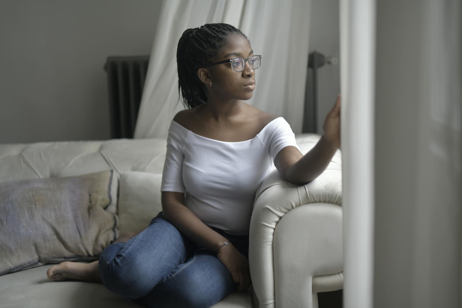 A woman looking out a window, reflecting on why the same relationship keeps arriving
