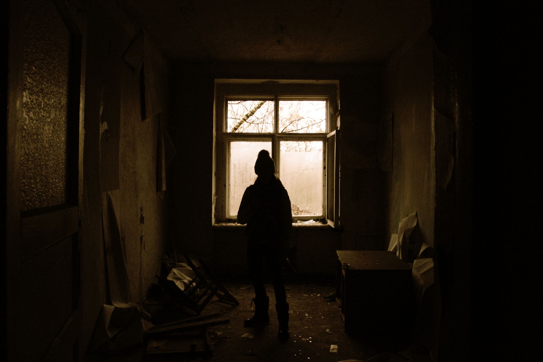 Solitary figure standing in dim room near window — the inner sense of an attachment