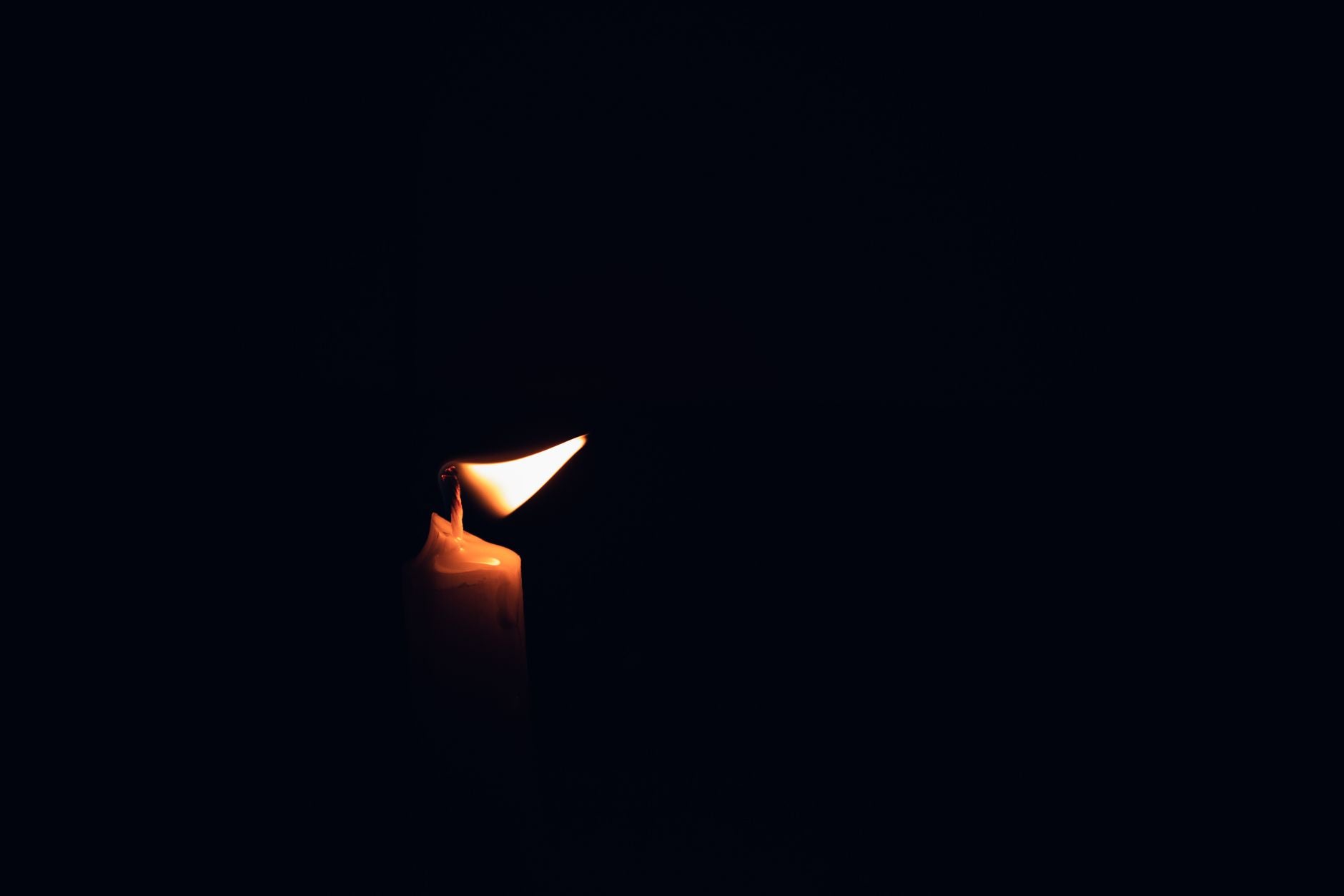 A single burning candle in darkness — returning attention to a single point