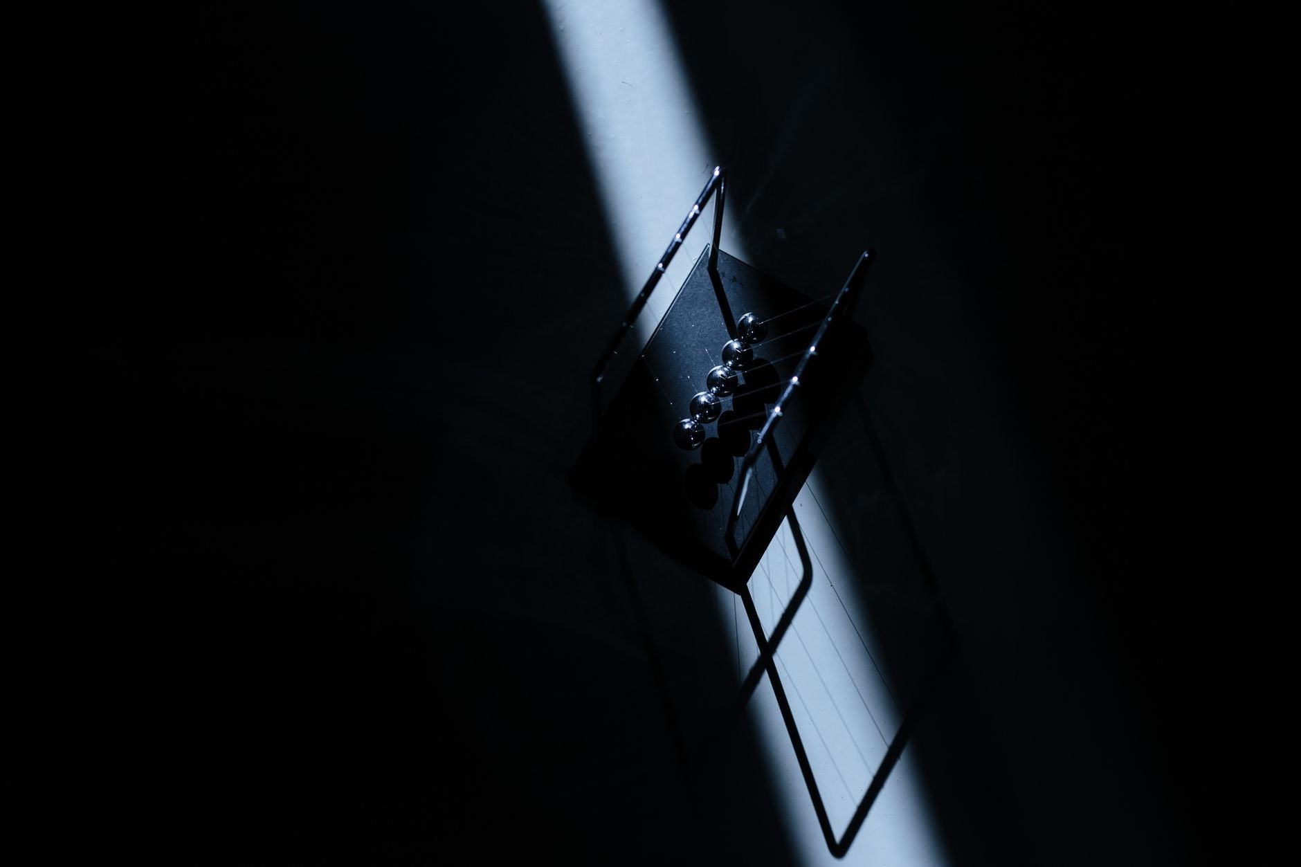A pendulum mid-swing photographed against a dim background, illustrating the Hermetic principles of polarity and rhythm in motion