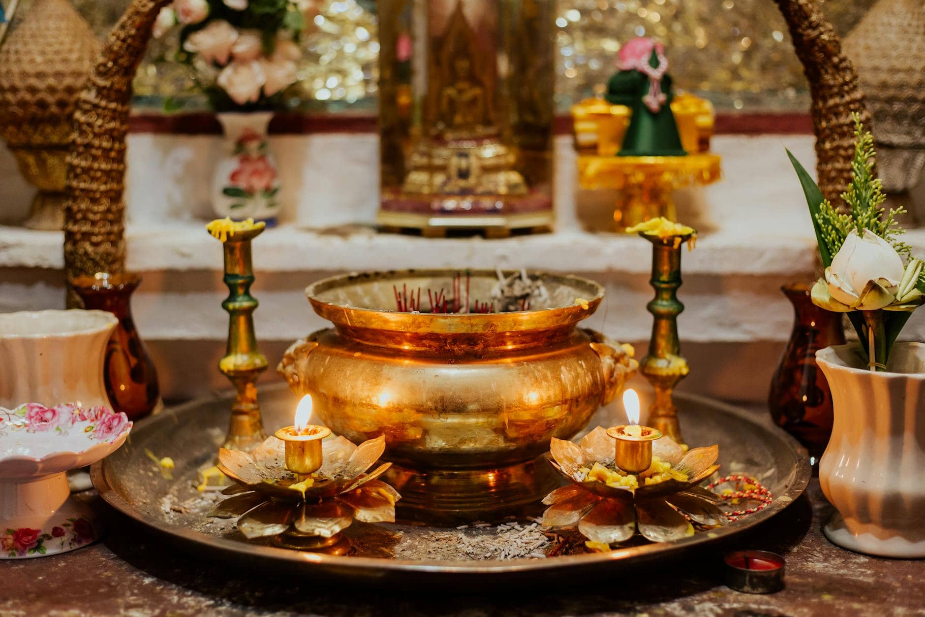 Golden vessel and wax candles arranged as an offering on a temple tray