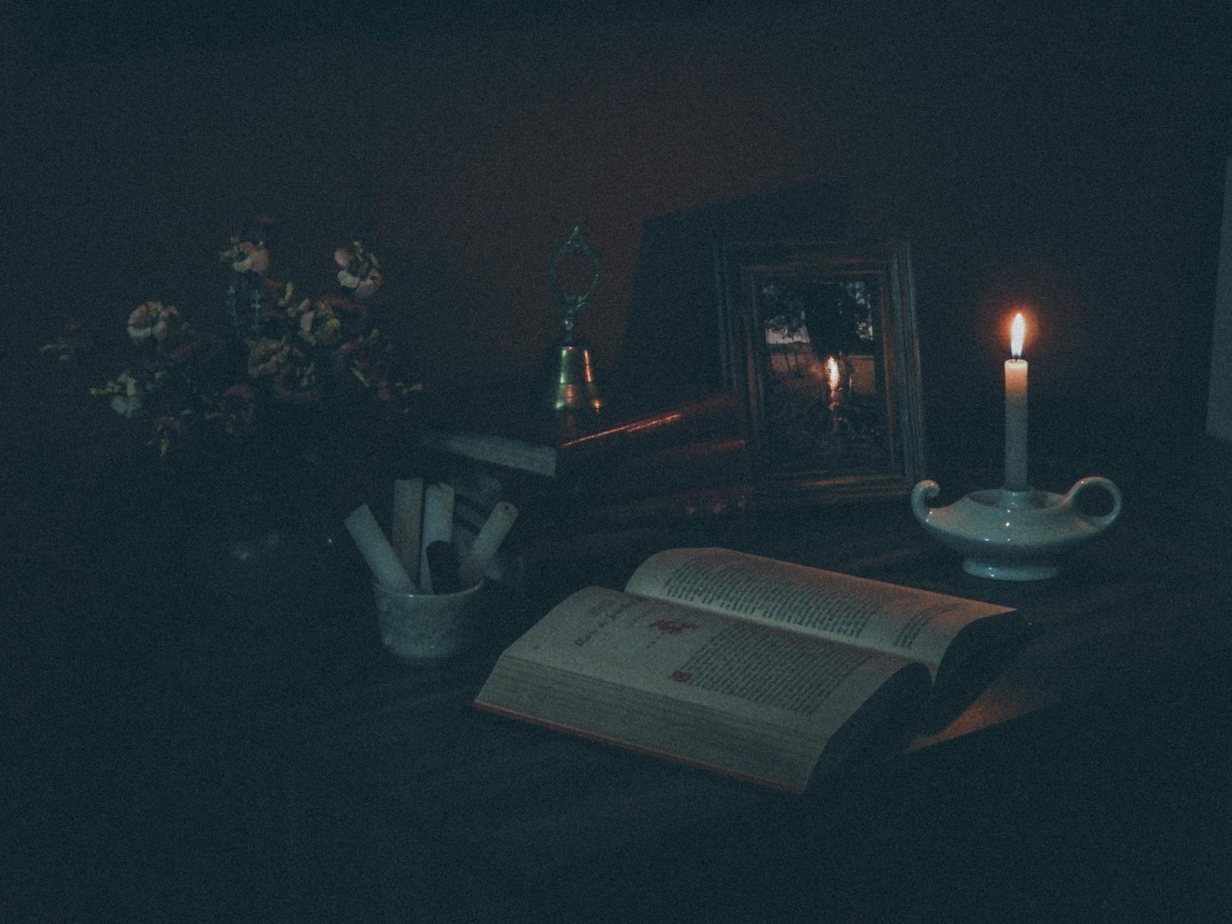 An open book lit by candlelight, the study at the root of occultism as an investigative tradition
