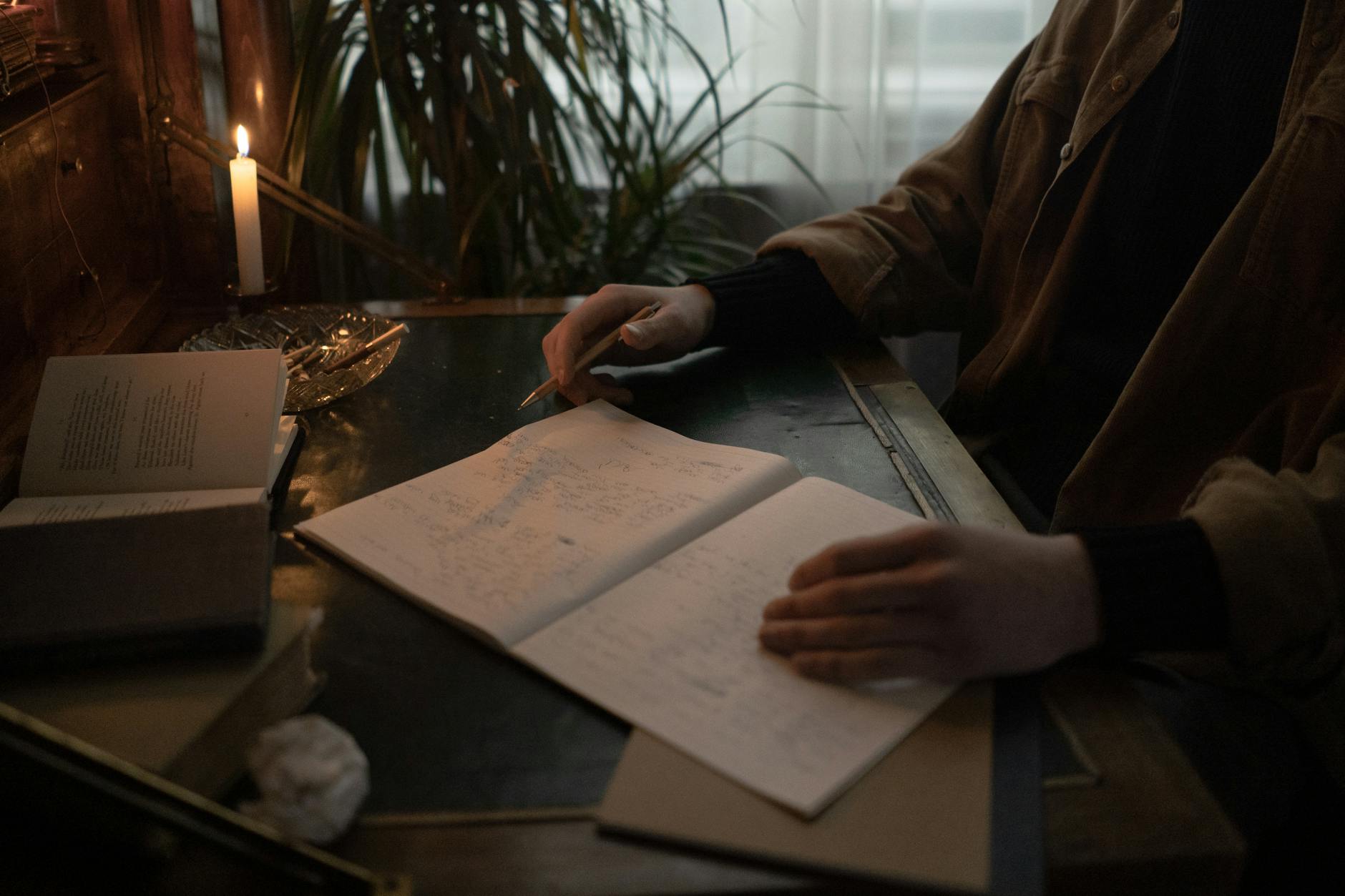 Person's hand sketching geometric symbols in a leather journal by candlelight, sigil construction